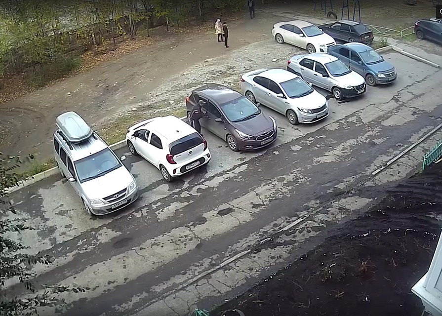 Мужчина, не смущаясь прохожих, пытается вскрыть чужую машину. Фото: стоп-кадр видеозаписи, соцсети