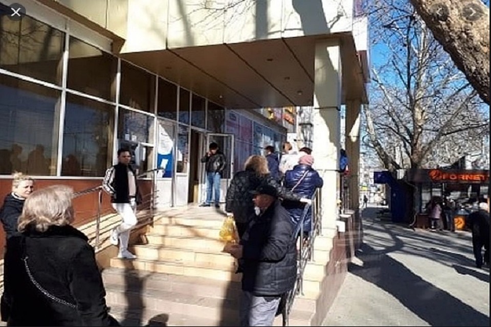 Люди терпеливо ждут на улице, чтобы зайти в магазин.