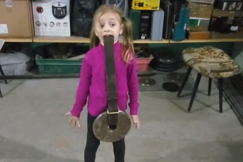 4-летняя дочь начала подражать папе и уже в состоянии поднять зубами половину своего веса. Фото: youtube.com/ UATV Russian