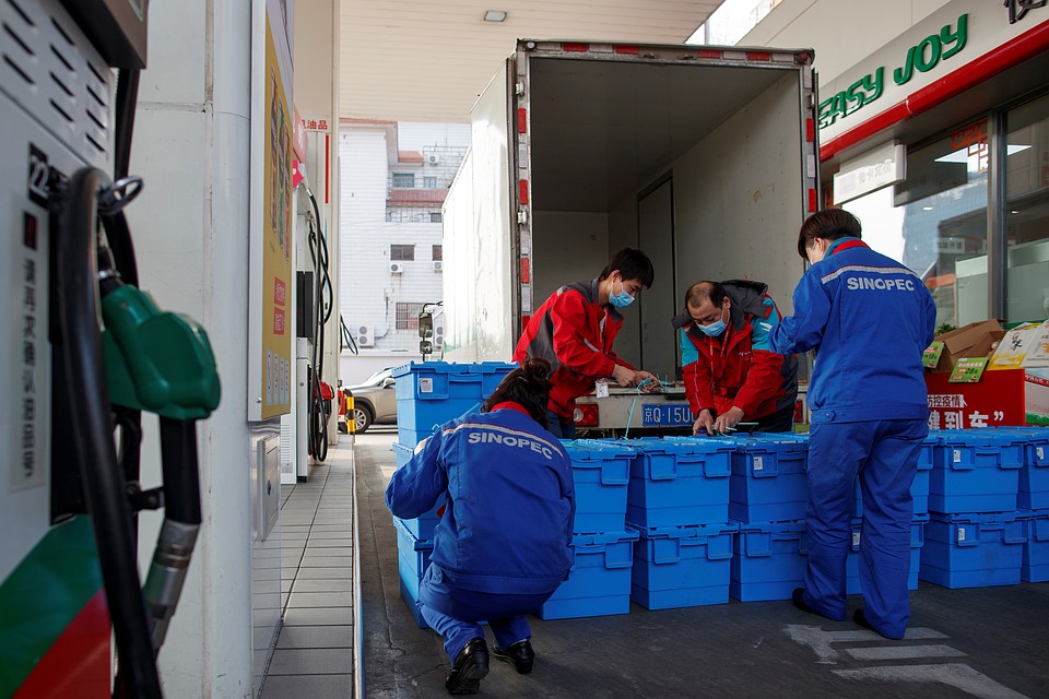 Рабочие разгружают продукты на заправке в Пекине. Из-за ограничений и закрытий магазинов, продукты теперь можно купить здесь Фото: REUTERS