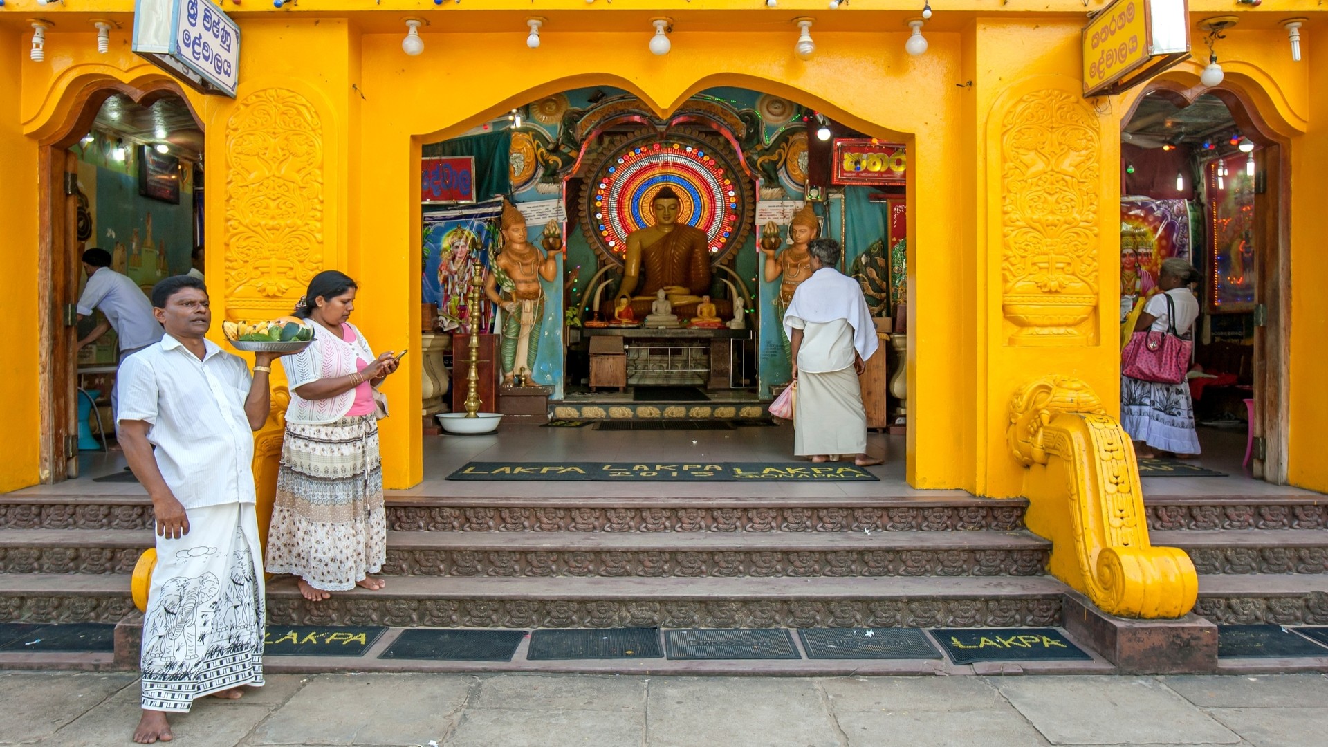 Посетители храма Катарагама стоят с подношениями перед буддийской святыней.