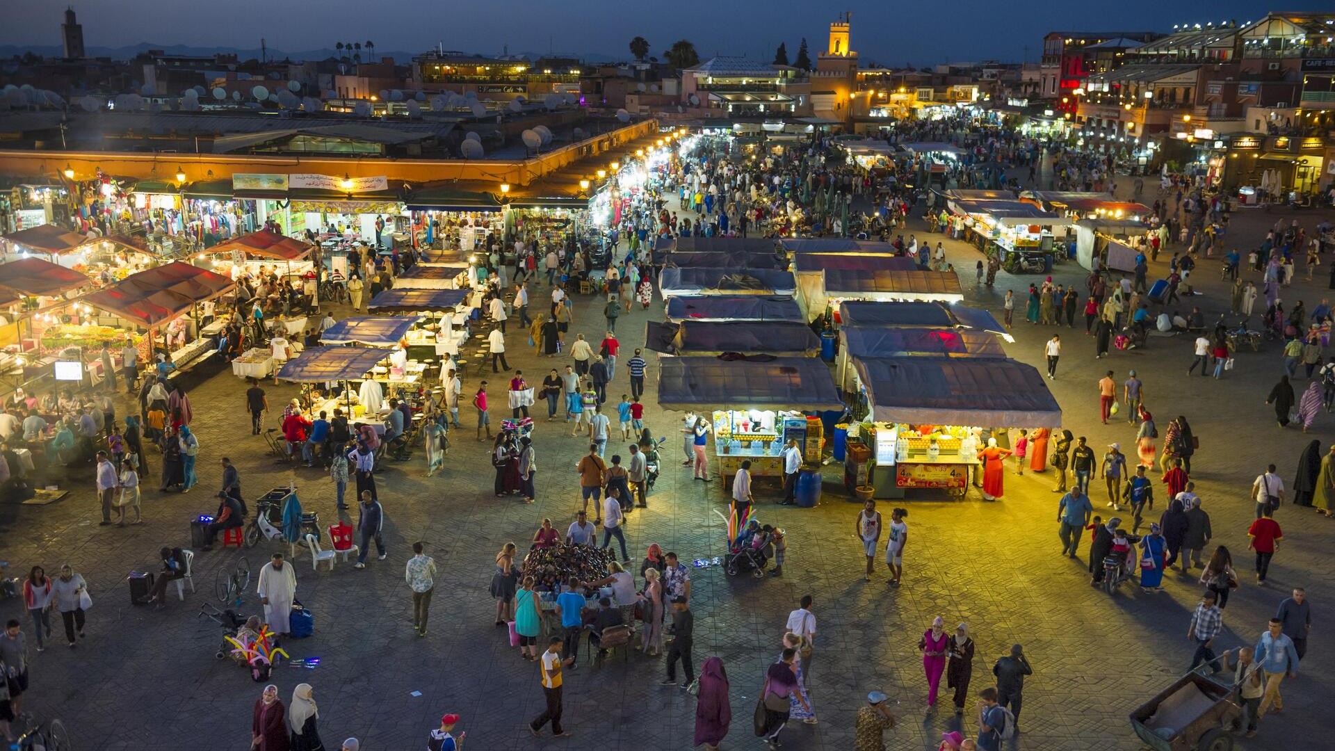 Много людей на площади Джемаа-эль-Фна в вечернем свете, Марракеш.